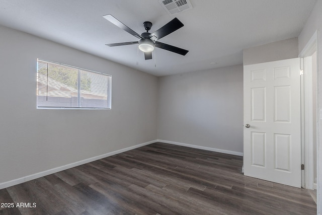 empty room featuring visible vents, a ceiling fan, baseboards, and dark wood-style floors