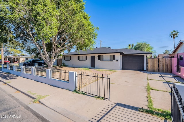 ranch-style house featuring a garage, a gate, a fenced front yard, and concrete driveway