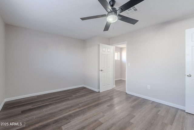 spare room featuring baseboards, ceiling fan, visible vents, and wood finished floors