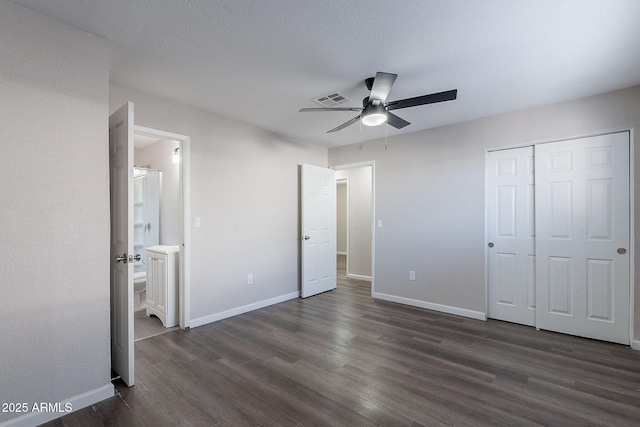 unfurnished bedroom featuring visible vents, connected bathroom, baseboards, and dark wood-type flooring