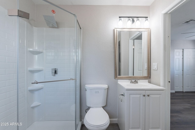 bathroom with vanity, toilet, a shower stall, wood finished floors, and visible vents