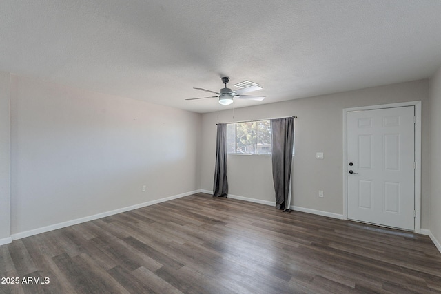 spare room featuring ceiling fan, a textured ceiling, visible vents, baseboards, and dark wood-type flooring