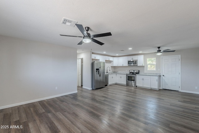 unfurnished living room featuring a ceiling fan, dark wood-type flooring, and visible vents