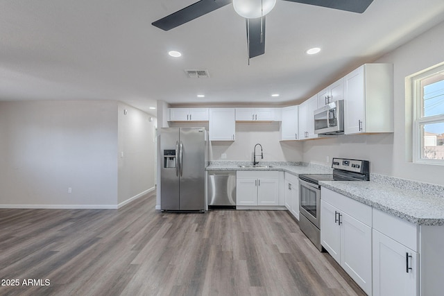 kitchen with white cabinets, stainless steel appliances, wood finished floors, and visible vents