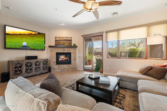 living room with a ceiling fan, a tile fireplace, visible vents, and tile patterned floors