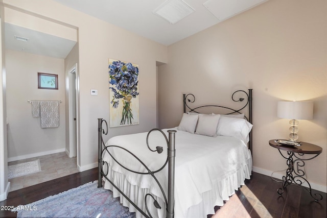 bedroom with baseboards, visible vents, and wood finished floors