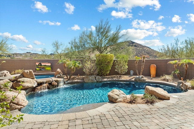 view of swimming pool featuring a fenced in pool, a fenced backyard, a mountain view, and a hot tub