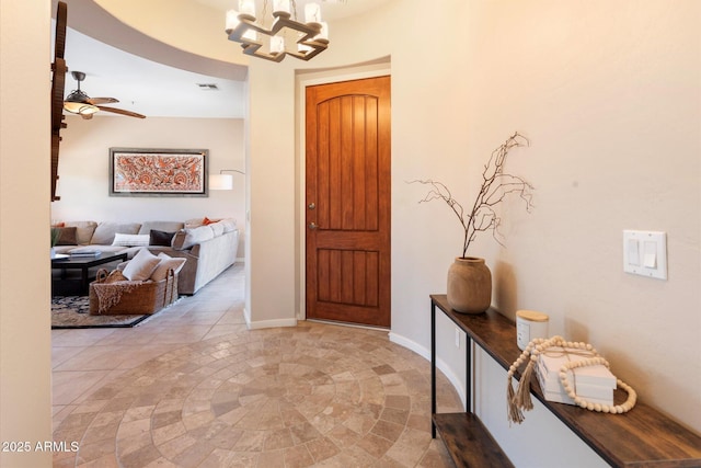 foyer entrance with visible vents, baseboards, and ceiling fan with notable chandelier