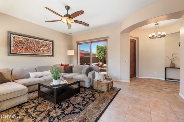 living room with light tile patterned floors, baseboards, arched walkways, and a ceiling fan