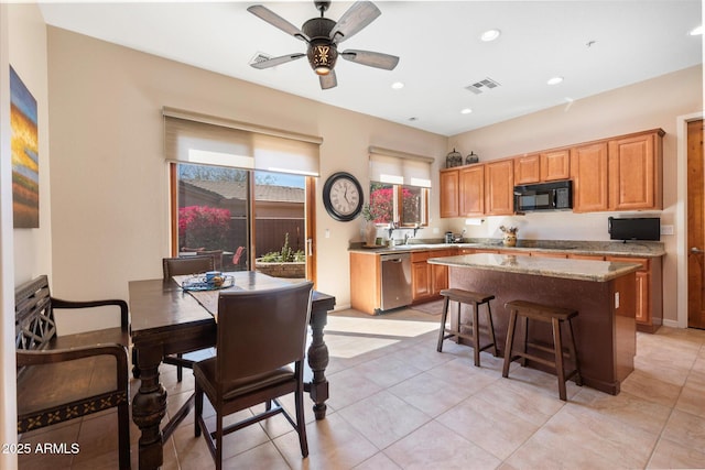 kitchen featuring ceiling fan, a kitchen island, a kitchen breakfast bar, black appliances, and recessed lighting