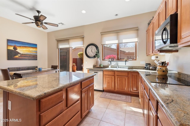 kitchen featuring light tile patterned flooring, a kitchen island, visible vents, light stone countertops, and black appliances