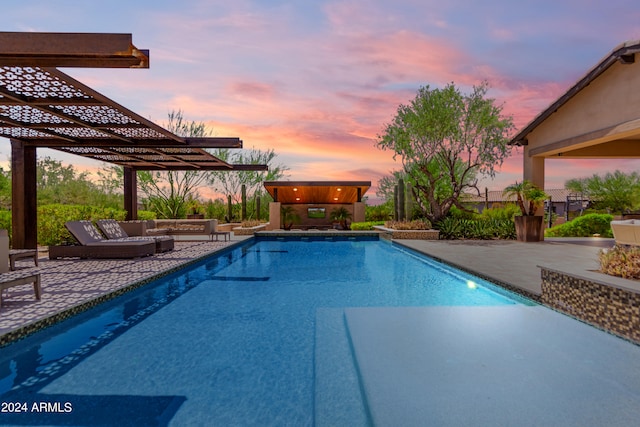 pool at dusk with a pergola and a patio area