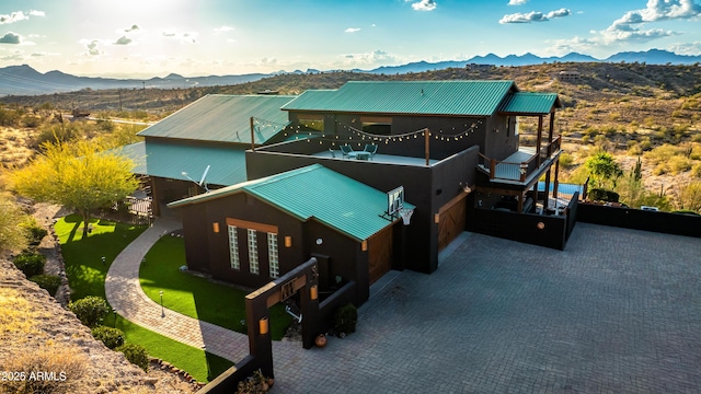 view of front facade with metal roof, a balcony, a mountain view, a garage, and decorative driveway