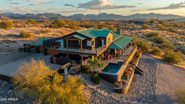 rear view of property with a mountain view and an in ground hot tub