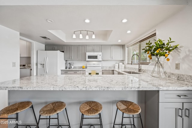14830 N 28th Pl, Phoenix, AZ 85032 - kitchen featuring white appliances, a tray ceiling, recessed lighting, gray cabinets, and light stone counters