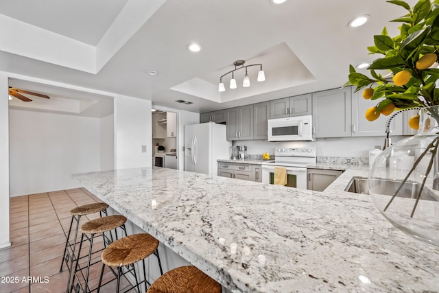 14830 N 28th Pl, Phoenix, AZ 85032 - kitchen with a tray ceiling, white appliances, light stone countertops, a peninsula, and gray cabinets