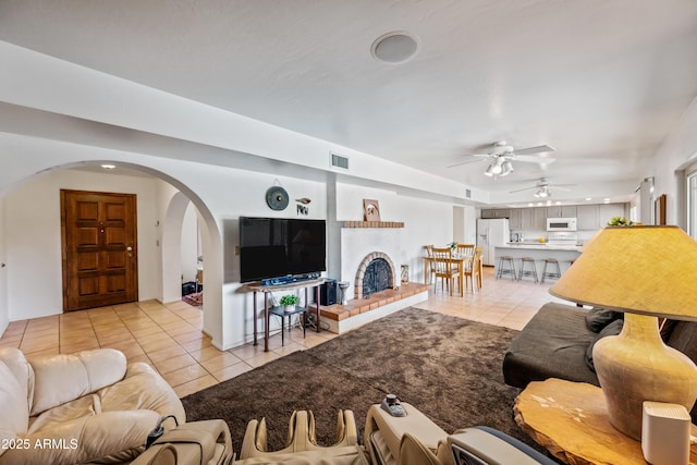 14830 N 28th Pl, Phoenix, AZ 85032 - living area with light tile patterned flooring, arched walkways, a ceiling fan, and a brick fireplace