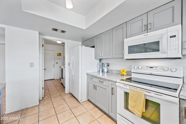 14830 N 28th Pl, Phoenix, AZ 85032 - kitchen featuring white appliances, gray cabinetry, light tile patterned floors, light stone counters, and a raised ceiling
