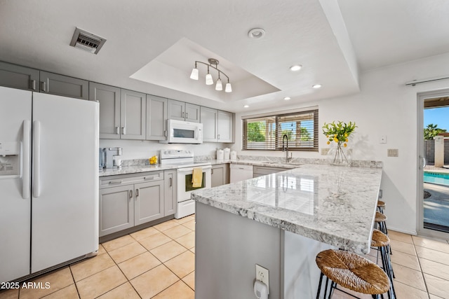 14830 N 28th Pl, Phoenix, AZ 85032 - kitchen with white appliances, a peninsula, a breakfast bar, light tile patterned floors, and gray cabinets