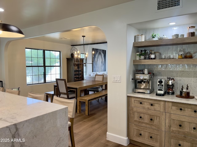 5556 E Sandra Ter, Scottsdale, AZ 85254 - bar with arched walkways, wood finished floors, backsplash, pendant lighting, and a chandelier