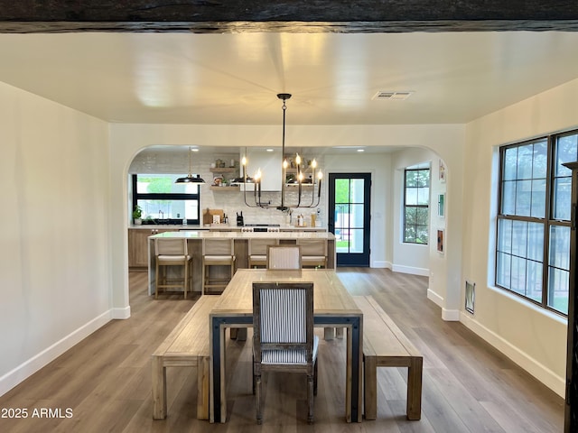 5556 E Sandra Ter, Scottsdale, AZ 85254 - dining space with arched walkways, wood finished floors, and a chandelier