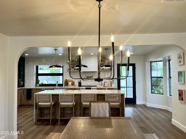 5556 E Sandra Ter, Scottsdale, AZ 85254 - kitchen with arched walkways, tasteful backsplash, dark wood-style floors, and a spacious island