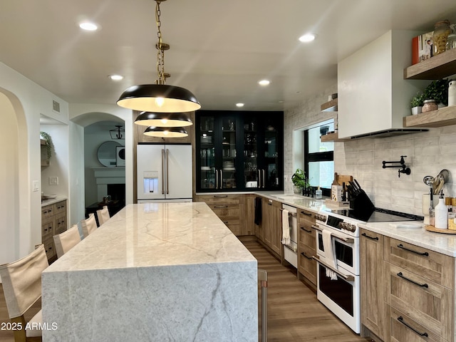 5556 E Sandra Ter, Scottsdale, AZ 85254 - kitchen featuring white appliances, open shelves, arched walkways, wood finished floors, and a center island