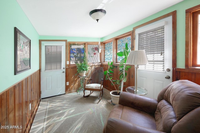 sitting room featuring light carpet and wood walls