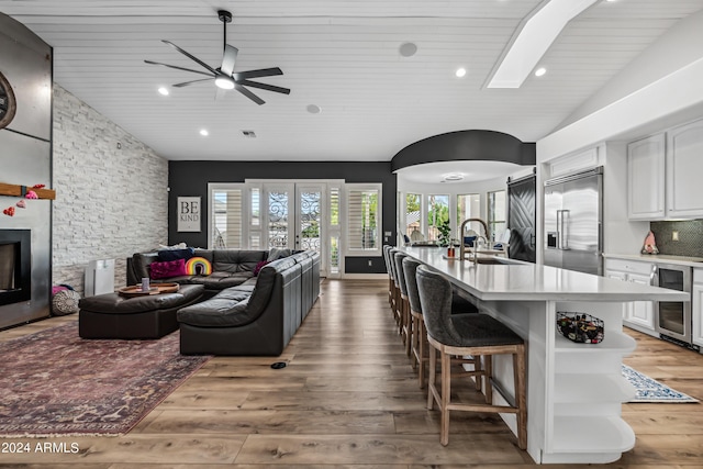 kitchen featuring sink, beverage cooler, built in refrigerator, white cabinets, and hardwood / wood-style flooring