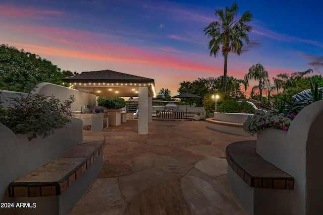 patio terrace at dusk featuring area for grilling and sink