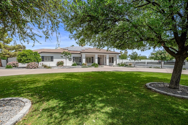 view of front of property with a front yard and solar panels