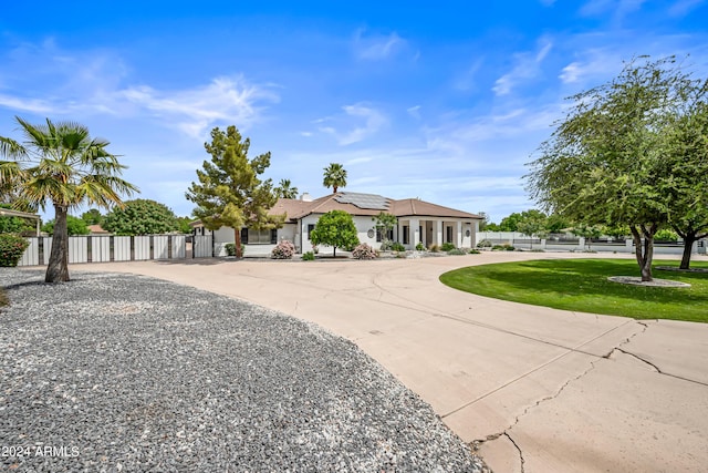 single story home featuring a front lawn and solar panels