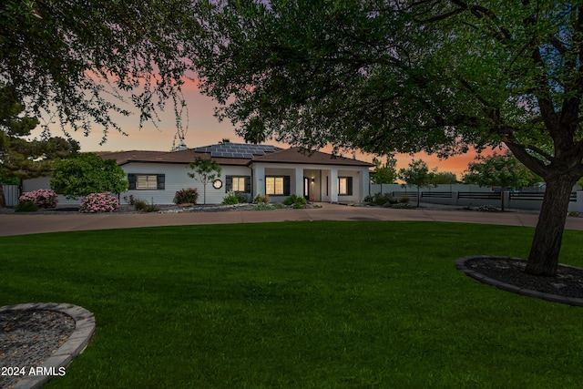 view of front of house with solar panels and a yard