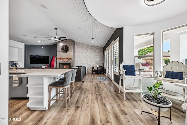 kitchen featuring a kitchen breakfast bar, a large fireplace, a healthy amount of sunlight, and light wood-type flooring