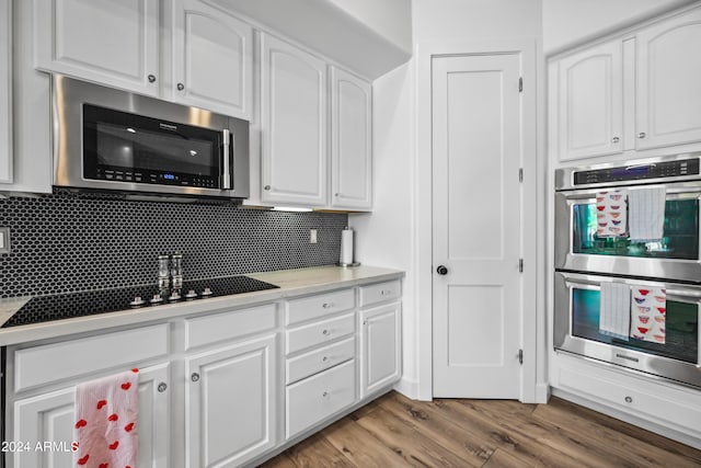 kitchen featuring decorative backsplash, white cabinetry, stainless steel appliances, and hardwood / wood-style flooring