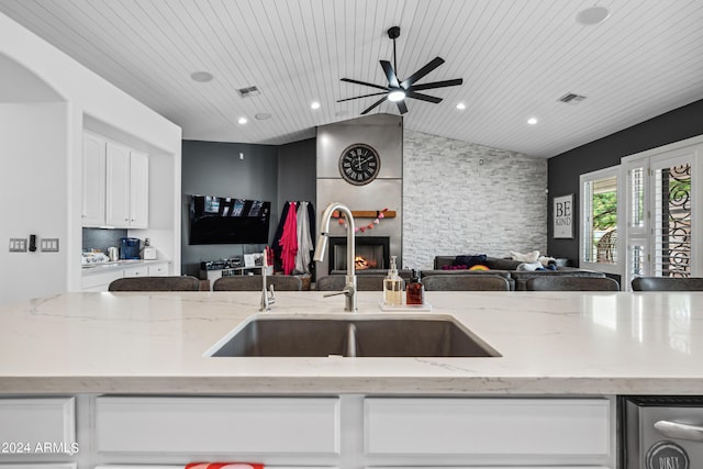 kitchen with light stone counters, sink, wooden ceiling, and lofted ceiling