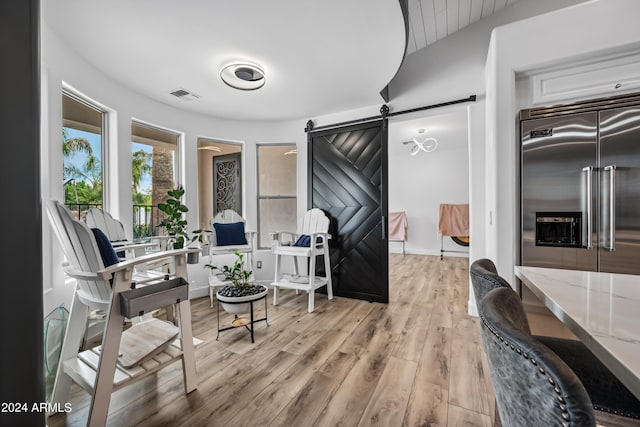 sitting room with a barn door and light hardwood / wood-style flooring