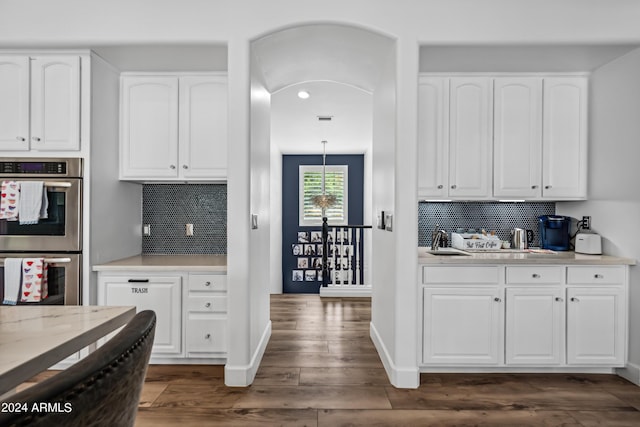 kitchen featuring backsplash, white cabinets, stainless steel double oven, and dark hardwood / wood-style floors