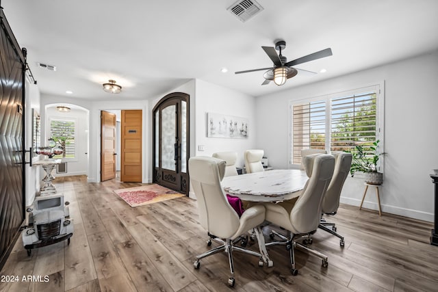 dining room featuring ceiling fan, a barn door, and light wood-type flooring