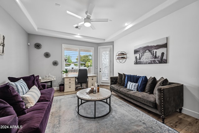 living room featuring a tray ceiling, hardwood / wood-style flooring, and ceiling fan