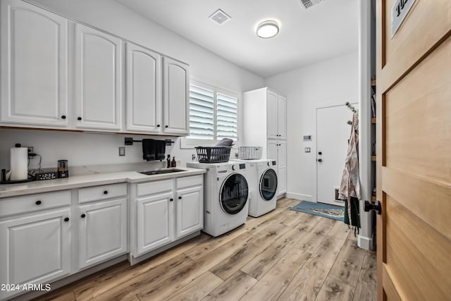 laundry area featuring washer and dryer, light hardwood / wood-style flooring, cabinets, and sink