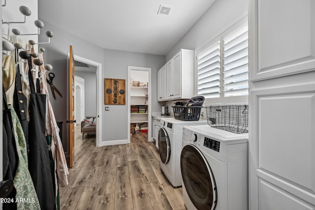 washroom with cabinets, light hardwood / wood-style floors, and washer and clothes dryer