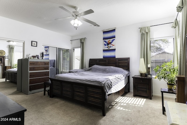 bedroom featuring light colored carpet, multiple windows, and ceiling fan