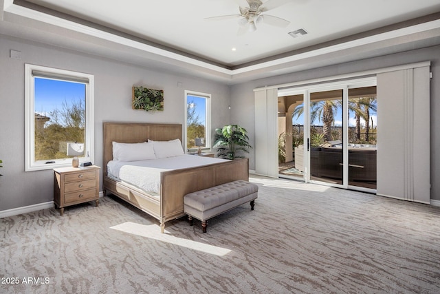 carpeted bedroom featuring a raised ceiling, access to exterior, and ceiling fan