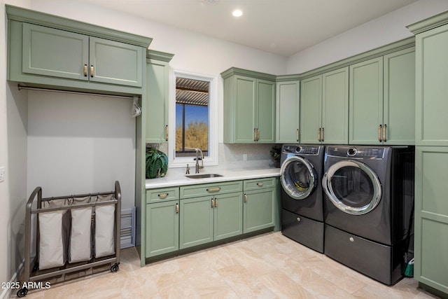 clothes washing area featuring sink, washer and clothes dryer, and cabinets