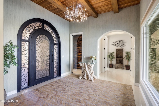 entryway with a towering ceiling, beam ceiling, a chandelier, and wooden ceiling