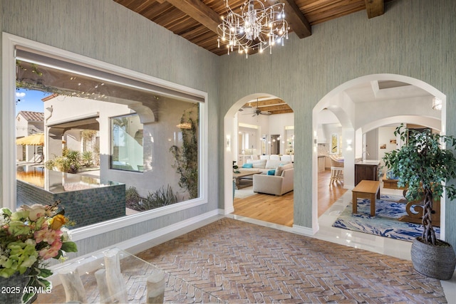 interior space featuring a towering ceiling, an inviting chandelier, and beam ceiling