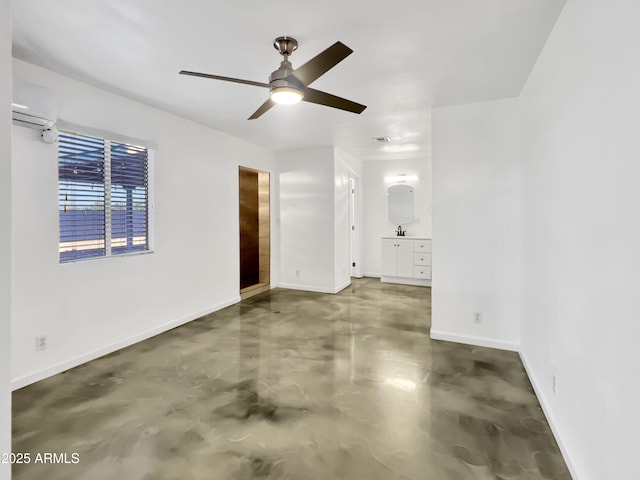 unfurnished room featuring a wall mounted AC, finished concrete floors, a sink, ceiling fan, and baseboards