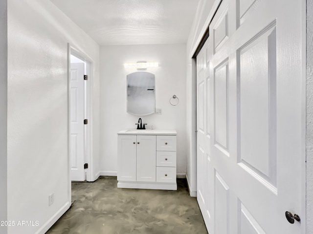 bathroom featuring baseboards, concrete flooring, and vanity