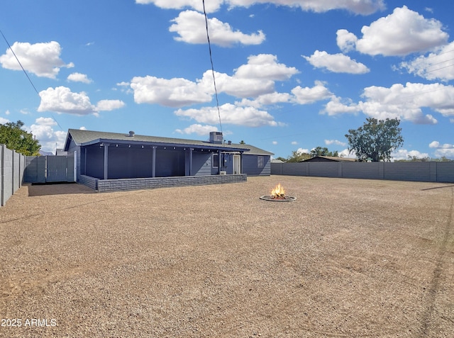 rear view of property with a fire pit, cooling unit, a fenced backyard, and a sunroom